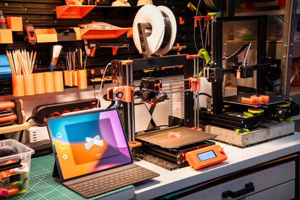About A high-tech workshop featuring 3D printers and a tablet on a desk, showcasing modern innovation.